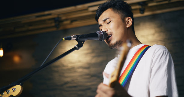 年轻的亚洲男性音乐家穿着休闲服，在歌手唱歌的同时弹着电吉他图片下载