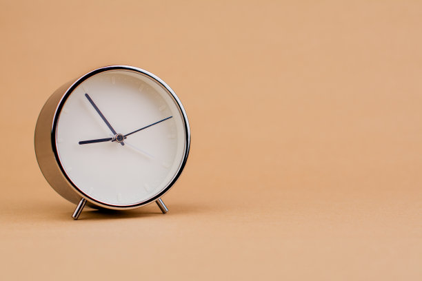 闹钟。漂亮的现代时钟躺在纸的背景上。工作时间，考勤时间，停工时间，下班时间，有时间观念图片下载