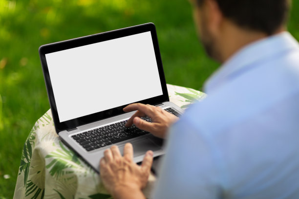 一名男子在自家花园里使用笔记本电脑图片下载