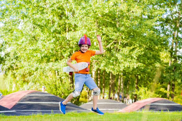 快乐快乐的男生戴着头盔拿着滑板跳，跑在滑板公园玩运动，骑，玩得开心图片下载