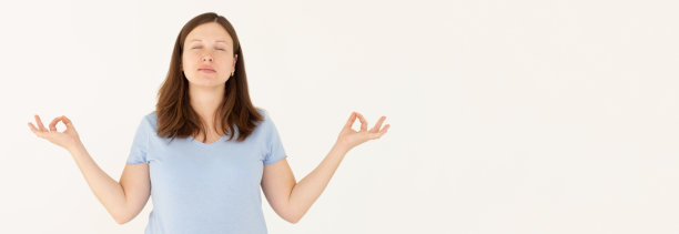 一位用心平和的白人孕妇在室内冥想，双手做手印手势，闭上眼睛，在长时间的工作后试图放松，在白色的墙壁上做瑜伽手势图片下载