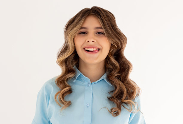 阴郁的黑发女子，波浪头发，对着镜头做鬼脸，伸出舌头。积极的女孩在室内玩得开心图片下载