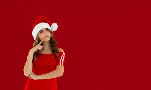 有趣的漂亮女士的照片庆祝寒假梦幻般的看空空间认为家庭聚会手放在下巴圣诞概念戴圣诞帽红色孤立的红色背景图片下载