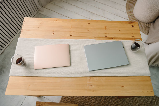 笔记本电脑放在家里办公室的桌子上。现代笔记本电脑。俯视图对象。风格的办公室木制办公桌，配有两台封闭的笔记本电脑和几杯咖啡。图片下载