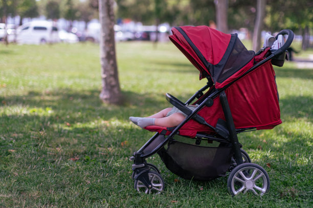 在温暖的夏日公园里，穿着袜子的小婴儿睡在舒适的马车里图片下载