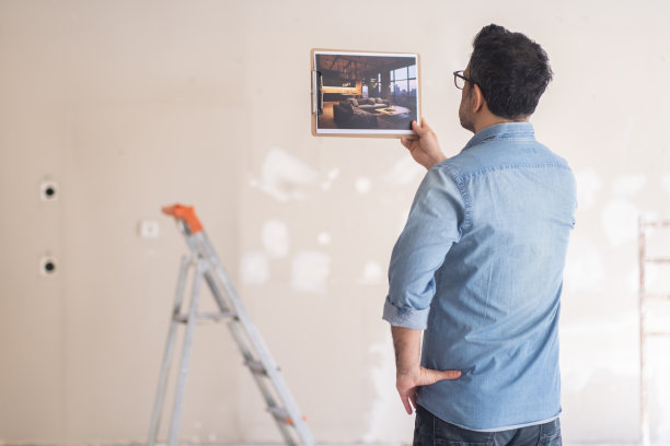 一名男子站在未完工的房间里，用阁楼式的室内设计检查图片图片下载