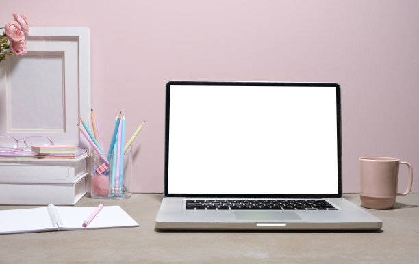 笔记本电脑的正面视图与空白屏幕，书籍和文具在女性办公桌上。图片下载