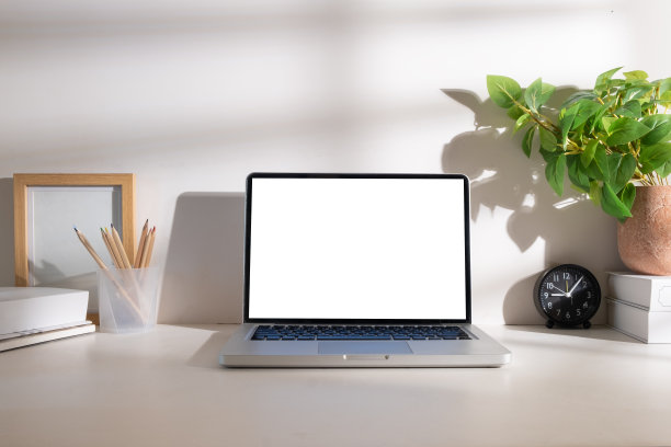 笔记本电脑与空显示器，记事本，咖啡杯，文具和室内植物在白色的桌子上。图片下载