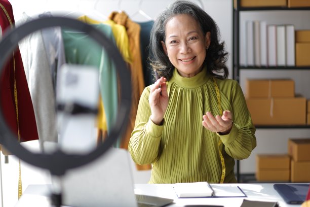 退休女性小企业主，她是裁缝和时装设计师。中小企业创业女性正在做直播出售她的衣服和商品。图片下载