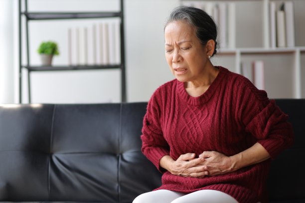 坐在家里沙发上的老妇人生病了，胃疼。图片下载