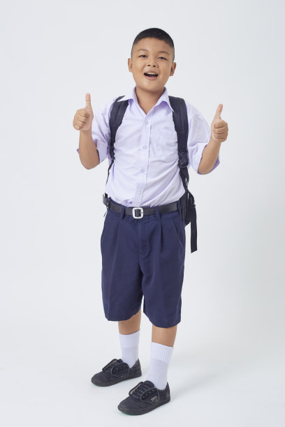 一个年轻的亚洲可爱的男孩站在泰国的校服，背包和书在一个白底横幅。回到学校图片下载
