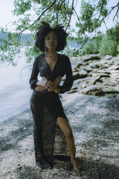 美丽的年轻非裔美国黑人妇女在阳光明媚的夏日里，在沙滩上与岩石和绿树合影。美容，天然皮肤身体护理和水疗。图片下载