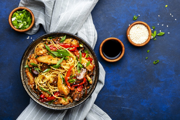 在陶瓷碗里用鸡肉、辣椒粉、香菇、香葱和芝麻炒鸡蛋面。亚洲菜。蓝石台面背景，俯视图图片下载