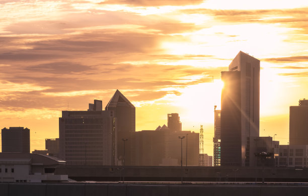 在一天的黄金时段，清晨日出的天空映衬着许多高楼大厦和高架道路图片下载
