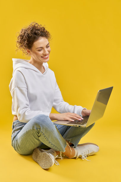 女孩坐在腿上，在笔记本电脑前工作。图片下载