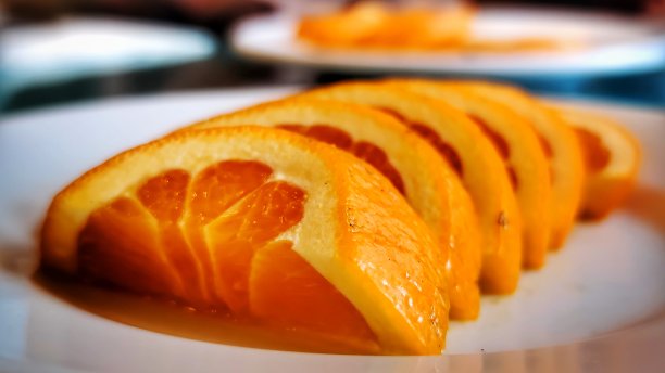切成片的新鲜黄橙子放在桌上的白色盘子里图片下载