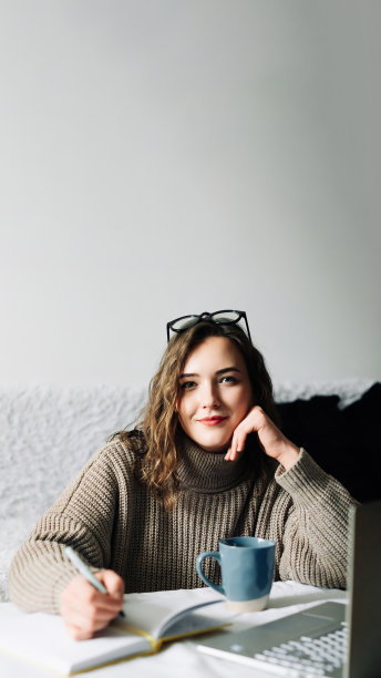 时尚而专注的女性公关经理，为网上商店制定内容计划，在家工作，带着笔记本电脑、笔记本和咖啡，看着相机图片下载