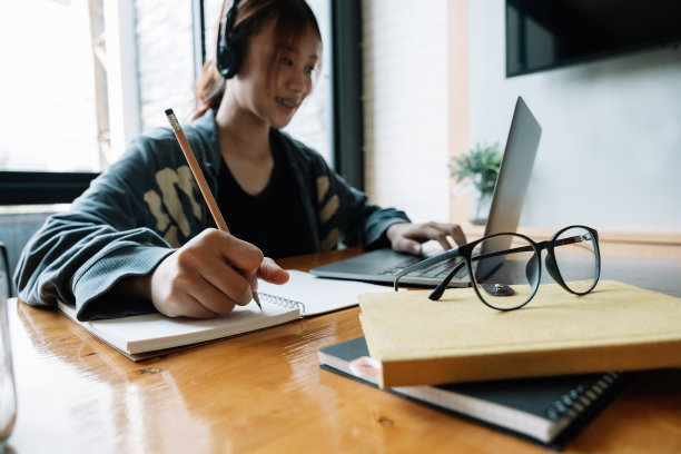 裁剪的亚洲妇女的照片写，制作清单，在笔记本电脑工作或学习在室内笔记本电脑-教育课程或培训，研讨会，教育在线概念图片下载