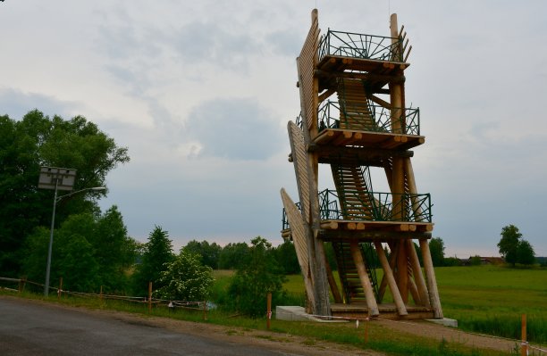 近景:在波兰一个多云的夏日里，在陡峭的山坡和森林或荒野旁的混凝土基座上，有装饰元素的木制瞭望台或岗楼的特写图片下载