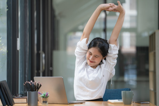 亚洲女商人，年轻迷人，伸展着肩膀和手臂的肌肉。由于久坐和工作，给商务人士和办公室综合症的概念。图片下载