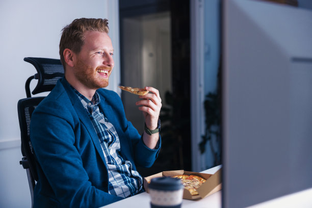 在办公室工作到很晚的商人吃着披萨喝着咖啡图片下载