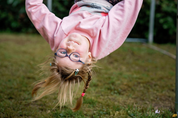 学龄前小女孩在户外单杠上攀爬和悬挂。快乐的女运动员在运动场上的体操棒上。快乐的孩子和暑假在操场上活动。图片下载