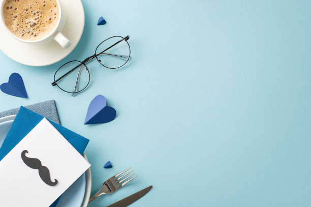 向你的父亲表达你对他的关心，在父亲节的餐桌布置上，包括感人至深的元素，俯视图手工制作的明信片放在盘子里，周围是配饰和其他装饰物品，蓝色背景图片下载