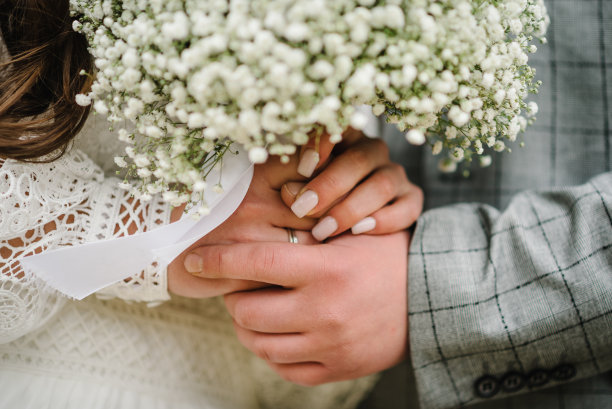 新郎新娘手牵着手，站在大自然后院的户外举行婚礼。带着乡村花束的乡村情侣。特写镜头。图片下载