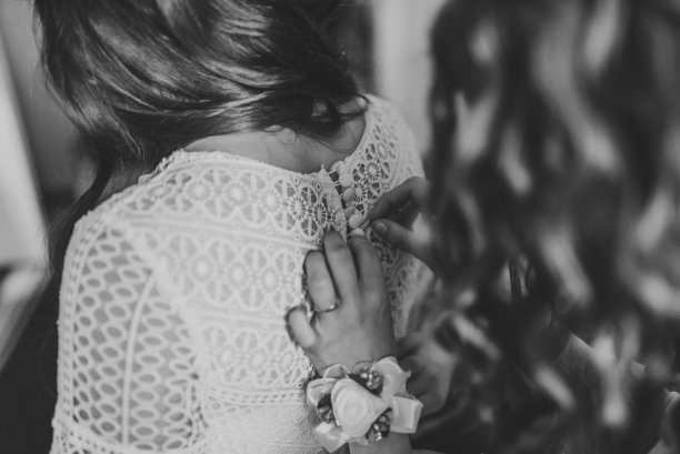 的婚礼。伴娘为新娘准备婚礼。姑娘们在婚礼前帮新娘系好礼服。豪华婚纱特写。新娘身上穿的礼服的背面。黑白照片图片下载