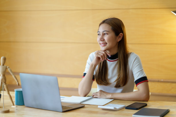 年轻漂亮的亚洲女学生在家里用笔记本电脑在线学习。图片下载