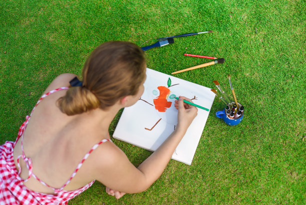 年轻的女艺术家和插画家，夏天躺在草坪上用铅笔画画图片下载