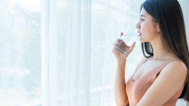 美丽的美女亚洲可爱的女孩感到快乐喝干净的水，为良好的健康在早上，享受时间在她的家白色的卧室背景-生活方式美女的概念图片下载