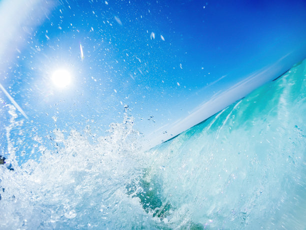 阳光下的海浪撞击海滩-地面透视拍摄泡沫绿松石浪。图片下载