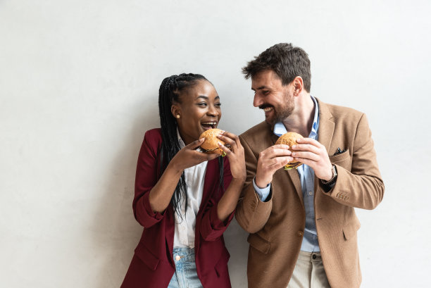 年轻商业男女吃汉堡做鬼脸图片下载
