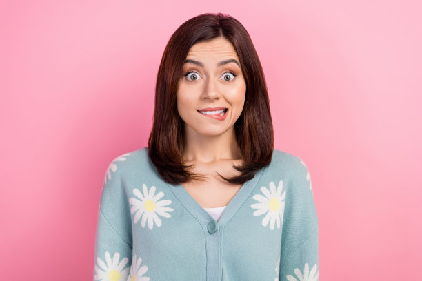 照片中时髦的有罪女士穿着绿松石色的衣服，咬着嘴唇，有问题，孤立的粉红色背景图片下载