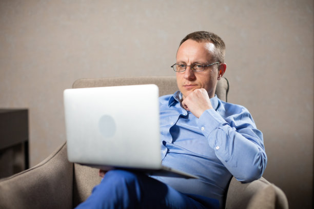 心理学家坐在扶手椅上，看着笔记本电脑的屏幕图片下载