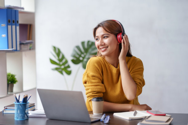 可爱的亚洲女人戴着耳机坐在家里开心地听音乐。图片下载