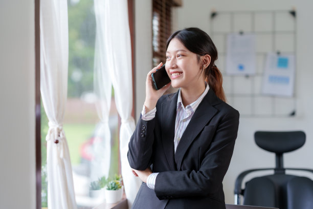 漂亮的亚洲女商人站在电话里友好地向办公室的客户解释各种任务。图片下载