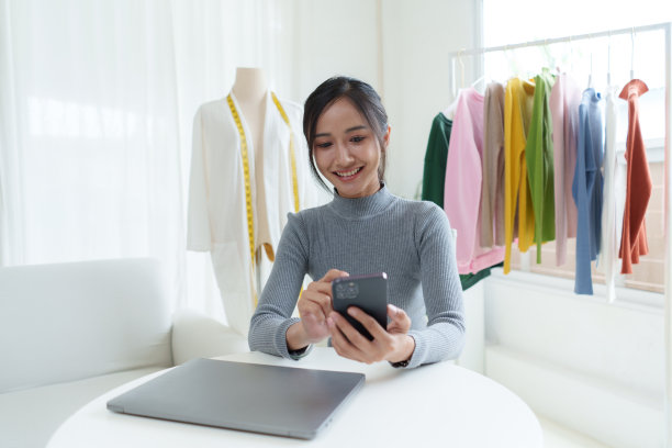 美丽的亚洲女性时装设计师坐在服装商店和工作室。在摄像机前录制视频博客直播。社交媒体概念上的商业在线影响者。图片下载