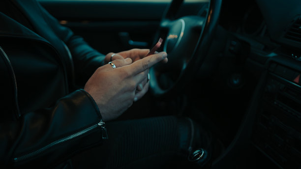 黄昏时分，一个男人在车里看手机的电影场景特写图片下载