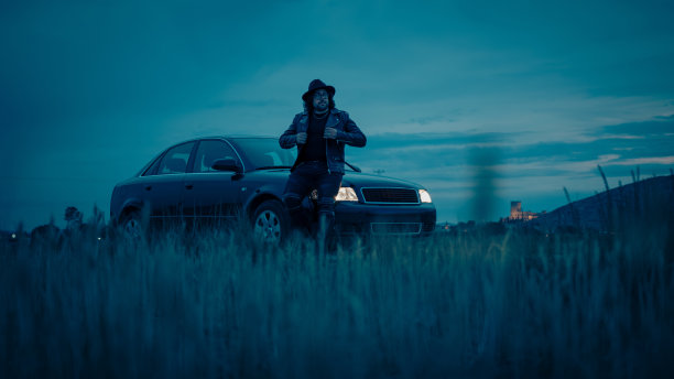 电影场景:一辆车里有一个戴帽子穿夹克的男人图片下载