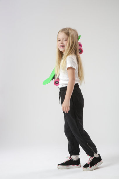 漂亮的金发小女孩的工作室肖像与滑板图片下载