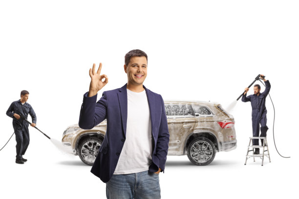 一名男子在做手势，工人们正在用高压清洗机清洗一辆SUV图片下载