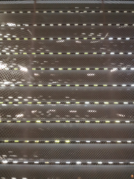 威尼斯百叶窗(遮阳板，法式百叶窗，百叶，板条或水平百叶窗)在白天关闭窗户以降低炎热的温度，太阳反射(斑点)通过白色花边(网)窗帘上板条之间的小空间图片下载