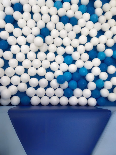 蓝色和白色的塑料玩具球围绕着皮革覆盖的软垫长凳图片下载
