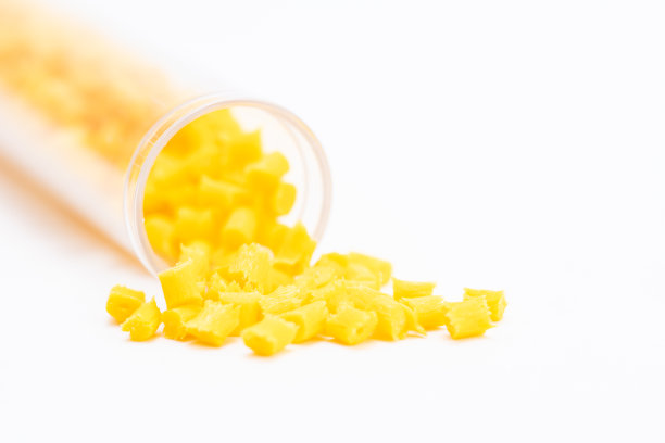 黄色颗粒从玻璃试管中掉落在白色底座上的创意镜头图片下载