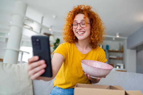 一位红发女子兴高采烈地拍下了她在网上订购的大麻，捕捉到了它到达时的兴奋。在这张迷人的图片中，她容光焕发的微笑展示了烹饪发现的乐趣。图片下载