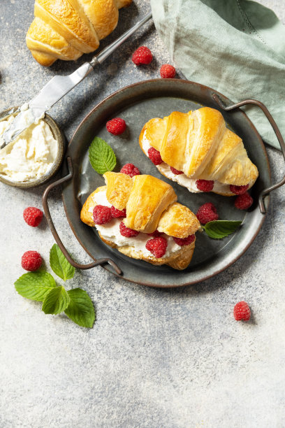 健康食品甜品理念，法式糕点。美味的新鲜出炉的牛角面包，奶油奶酪和覆盆子在石头背景。从上面看。副本的空间。图片下载