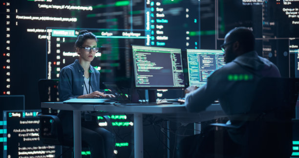 不同的年轻人在台式电脑上工作，周围是显示代码行的大屏幕。为生成式AI开发自主算法的专业计算机工程师。图片下载