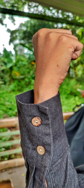 一只手穿着黑衬衫，上面有两个棕色纽扣图片下载